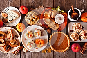 Autumn food table scene with pies, appetizers and desserts. Above view over a rustic wood background.