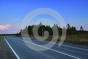 Autumn forest with country road at sunset. Colorful landscape with trees, rural road, sun in fall