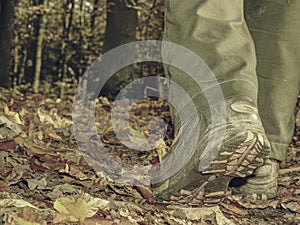 Woman in high leather shoes or boots walking on fallen leaves