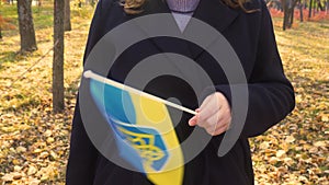 Autumn forest. Girl waving the yellow-blue flag of Ukraine (fixed camera)