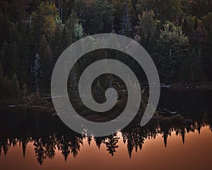 Autumn forest landscape and reflection in the lake at sunset. La Mauricie National Park, Canada