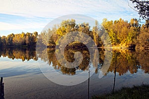 Autumn forest reflected in the calm waters of a lake makes a mirror effect