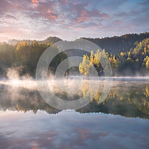 Autumn forest reflected in water. Colorful autumn morning in the mountains. Colourful autumn morning in mountain lake Foggy autumn