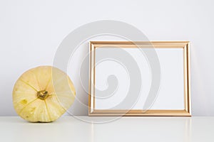 Autumn frame, background. Thanksgiving mockup with golden frame and yellow pumpkin. Halloween, fall minimal composition with copy