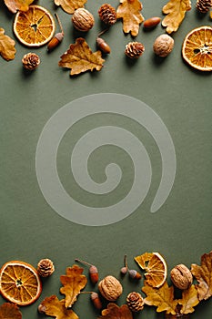 Autumn frame with dry oranges, fallen oak leaves, acorns, walnuts on vintage green background. Thanksgiving card mockup. Flat lay