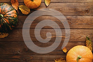 Autumn frame made of pumpkins, dried fall leaves, apples, red berries, walnuts on wooden table. Thanksgiving, Halloween, Autumn