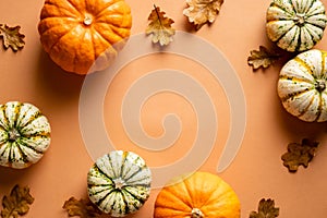 Autumn frame made of pumpkins, fallen oak leaves on vintage orange background. Flat lay, top view. Thanksgiving day greeting card