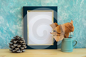 Autumn frame mockup, blue and golden border, tree branch with dry leaves in pitches, pine cone, concrete wall background, rustic