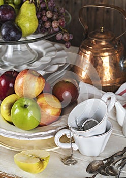 Autumn fruits, plates, cutlery and kitchen utencils on wooden table. Grapes, apples and pears on table