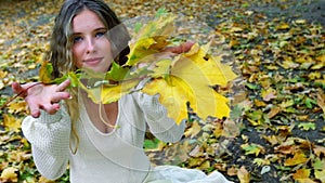 Autumn girl blowing on bouquet of fall leaves