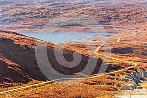 Autumn greenlandic orange tundra landscape with road to the lake and mountains in the background, Kangerlussuaq, Greenland