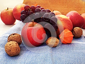 Autumn harvest, apples, walnuts, grapes, fizalis on a blue towel