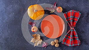 Autumn harvest festival and thanksgiving day table setting. Fallen leaves, pumpkin, apples, nuts, empty plate and checkered napkin