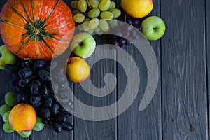 Autumn harvest of vegetables and fruits on a dark wooden background with a place for inscription. Pumpkin, peach, apples, grapes. photo