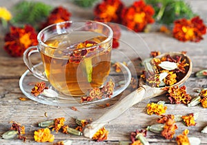 Autumn healing background. Folk medicine Glass of herbal tea with marigold flowers on wooden ancient background with dried flowers