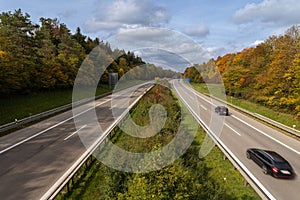 Autumn highway - cars are driving fast over a german Autobahn with colorful fall colors.
