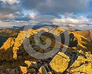 Autumn hiking in the mountains with massive rocks, dramatic skies and majestic mountains.