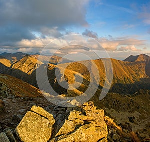 Autumn hiking in the mountains with massive rocks, dramatic skies and majestic mountains.