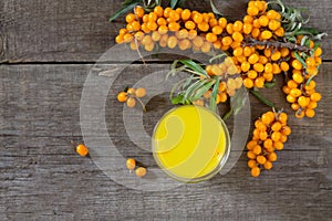Autumn hot drink. Tea with sea-buckthorn berries branch on vintage wooden background. Space for your text