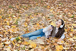 Autumn kid fashion. inspiration. happy childhood. back to school. girl among maple leaves relax in park. fall beauty in