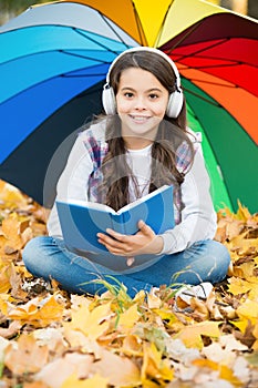 Autumn kid under colorful umbrella. feel the inspiration. happy childhood. back to school. girl read book wearing
