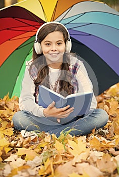 autumn kid under colorful umbrella. feel the inspiration. happy childhood. back to school. girl read book wearing