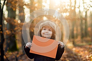 Autumn kids advertising and sale. Cute child showing blank placard with copy space for your text. Little boy holding