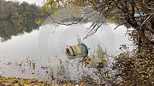 Autumn lake with old tyres in water, and gulls flying in background