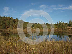 Autumn landscape. Autumn sky and forest reflected in the water surface of the pond