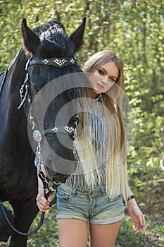 Beautiful brunette girl with long hair posing with a red horse in forest