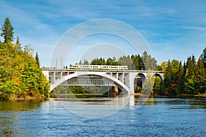 Autumn landscape of bridge with moving passenger train and Kymijoki river waters in Finland, Kouvola, Koria photo