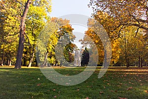 Jesenná krajina mestský park, gotický architektonický fragment historickej veže v strede, zelená tráva s jesenným lístím a farbou