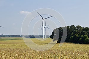 Autumn landscape with giant wind power turbines in a crop field