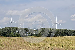 Autumn landscape with giant wind power turbines in a crop field
