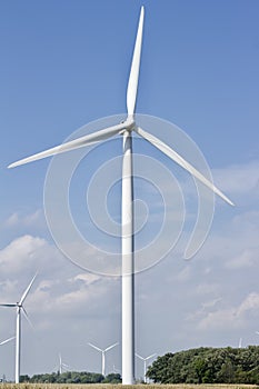 Autumn landscape with giant wind power turbines in a crop field