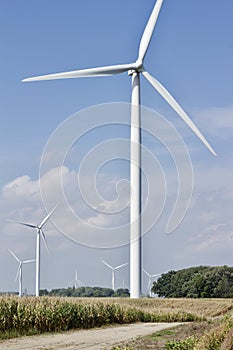 Autumn landscape with giant wind power turbines in a crop field