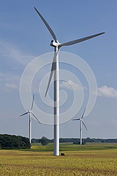 Autumn landscape with giant wind power turbines in a crop field