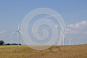 Autumn landscape with giant wind power turbines in a crop field