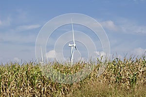 Autumn landscape with giant wind power turbines in a crop field