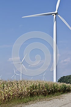 Autumn landscape with giant wind power turbines in a crop field