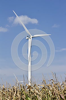 Autumn landscape with giant wind power turbines in a crop field