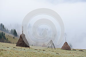 Autumn landscape with haystacks and fog in the mountains