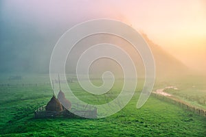 Autumn landscape with haystacks on the meadow at sunrise