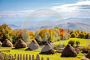 Autumn landscape with haystacks and mountains in the distance