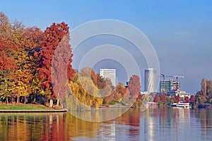 Autumn landscape in the Herastrau park. Colored trees and Floreasca City Center in background - landmark in Bucharest, Romania