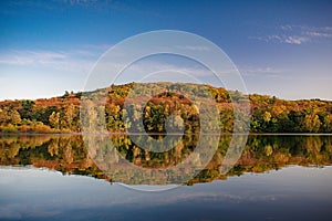 Autumn landscape. A lake with a smooth mirror surface of water and a forest on the shore in autumn colors.