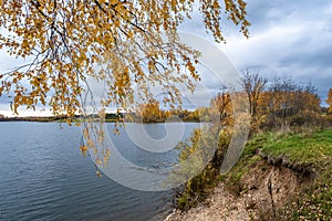 Autumn landscape with a large reservoir and birch trees with yellow leaves