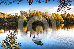 Autumn Landscape with A Lone Boat, Colorful Trees and Houses Reflected in Lake