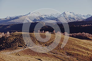 An autumn landscape of mountains on a trip with snow-covered winter peaks in the background