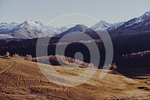 Autumn landscape of the nature of the mountains on a trip with snow-capped winter peaks in the background, off roads